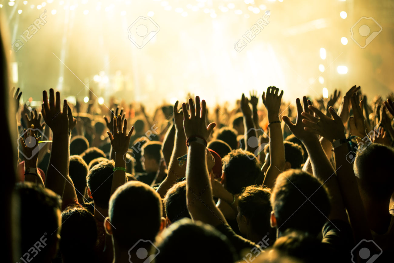 45720753-Audience-with-hands-raised-at-a-music-festival-and-lights-streaming-down-from-above-the-stage-Soft-f-Stock-Photo.jpg